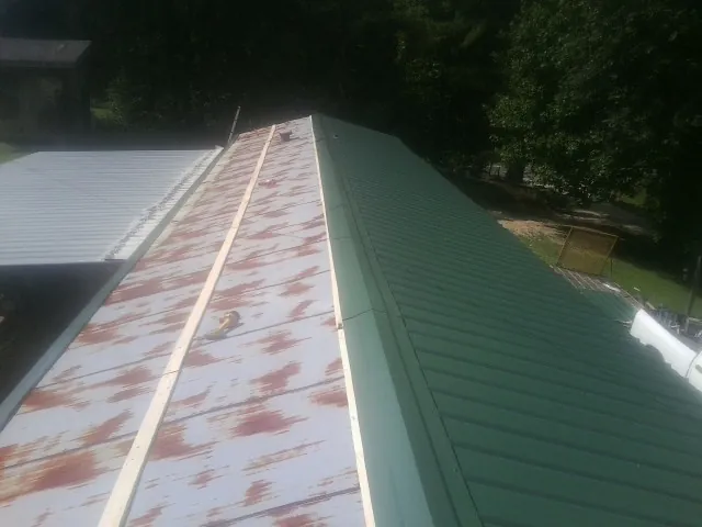 Old rusted panels beside newly installed green metal roofing — Wind Damage Roof Repair by Roofing Brothers in Morrisville