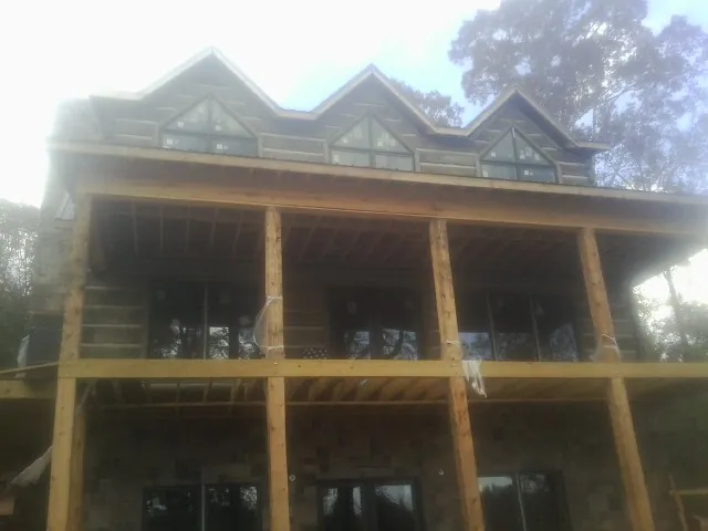 Dormers and porch framing on a large log home under construction — Roof Coating work by our crew in Morrisville