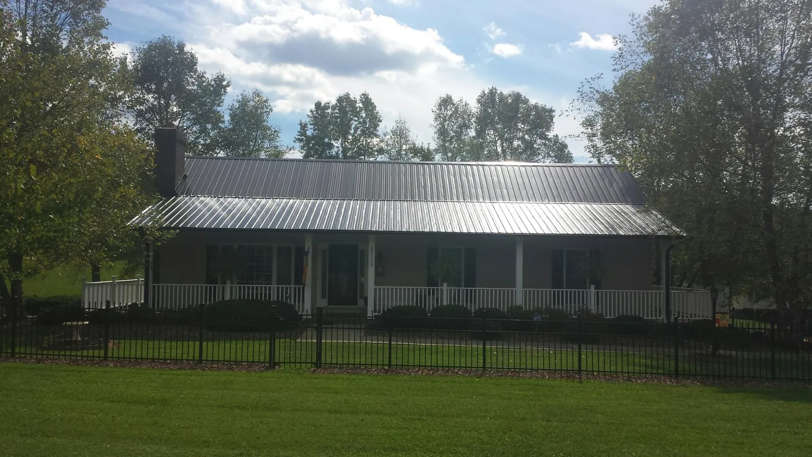 Gray metal roof on a brick ranch with a full width front porch — Gutter Guard Installation work by our crew in Morrisville